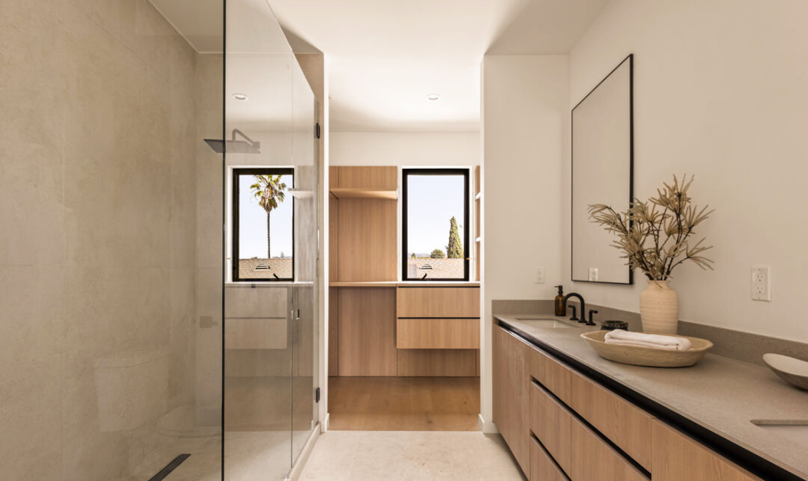 Primary bathroom remodel with walk-in glass shower and floating wood vanity